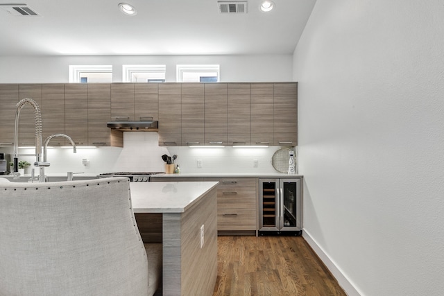 kitchen featuring beverage cooler, dark hardwood / wood-style floors, tasteful backsplash, a breakfast bar area, and stainless steel gas cooktop