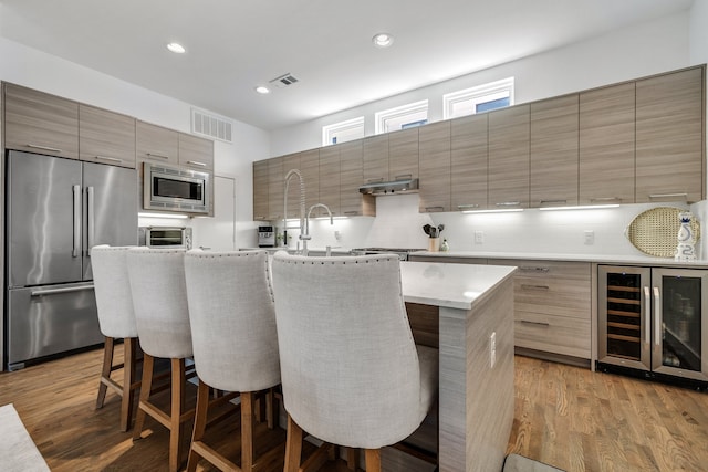 kitchen featuring a breakfast bar area, built in appliances, a center island, and light hardwood / wood-style floors