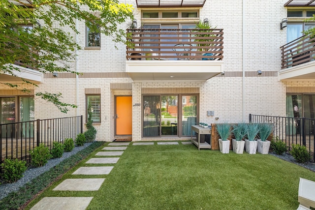 property entrance featuring a balcony and a lawn