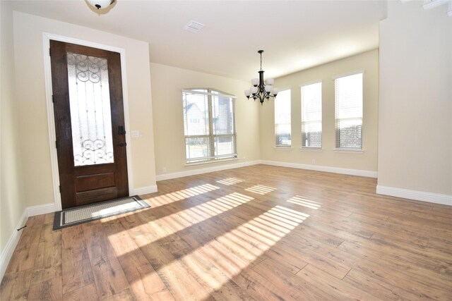 foyer entrance with a chandelier and light wood-type flooring