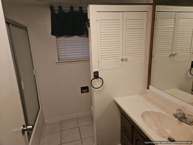 bathroom featuring tile patterned flooring, vanity, toilet, and a shower with shower door