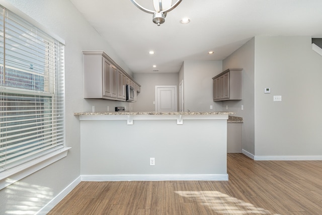 kitchen with a breakfast bar, light wood-type flooring, and kitchen peninsula