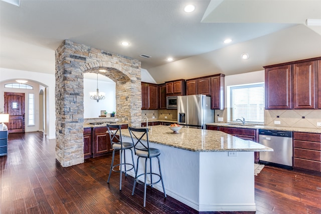 kitchen featuring dark hardwood / wood-style flooring, sink, stainless steel appliances, and a kitchen island with sink