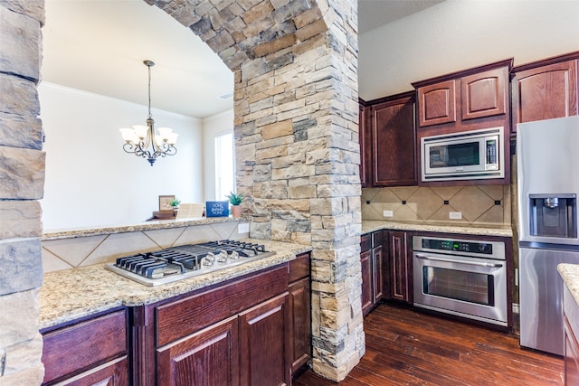 kitchen featuring light stone countertops, appliances with stainless steel finishes, backsplash, pendant lighting, and dark hardwood / wood-style floors