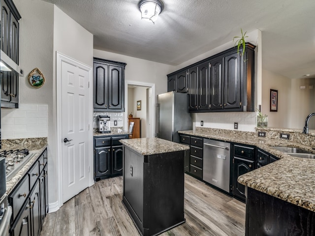 kitchen with appliances with stainless steel finishes, a center island, light hardwood / wood-style floors, and sink