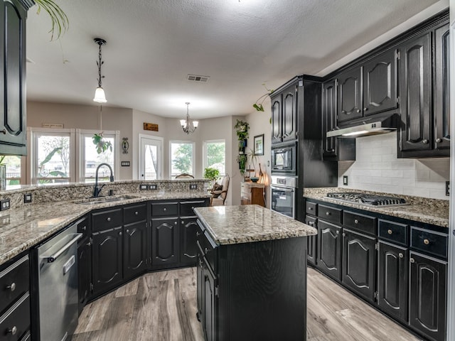 kitchen featuring sink, light hardwood / wood-style floors, pendant lighting, a kitchen island, and appliances with stainless steel finishes