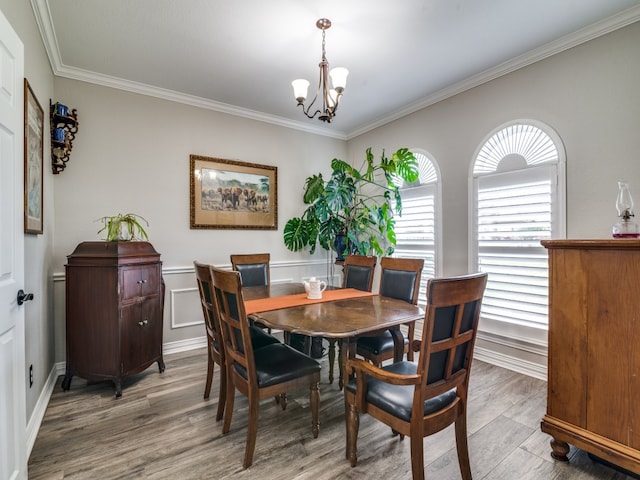 dining space featuring hardwood / wood-style floors, crown molding, and an inviting chandelier