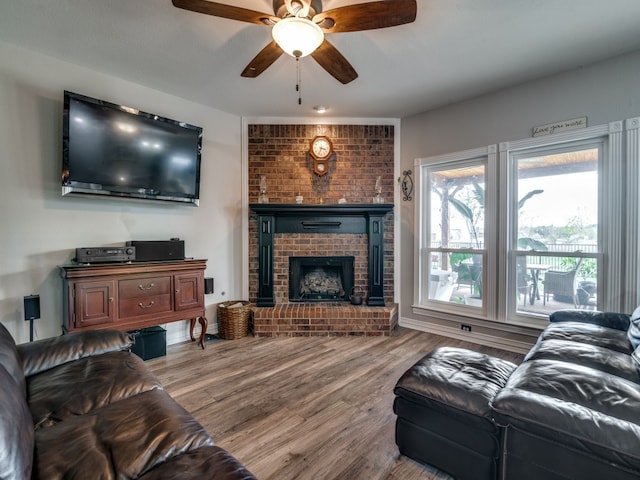 living room with ceiling fan, wood-type flooring, and a brick fireplace