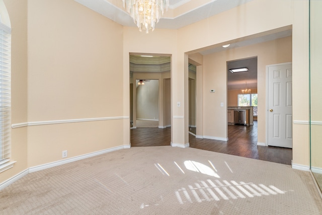 spare room with dark hardwood / wood-style flooring, ornamental molding, and a chandelier