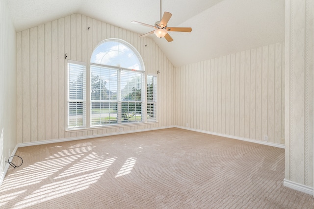 carpeted empty room featuring a textured ceiling, vaulted ceiling, and ceiling fan