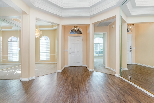 foyer entrance with a tray ceiling, hardwood / wood-style floors, a chandelier, and ornamental molding