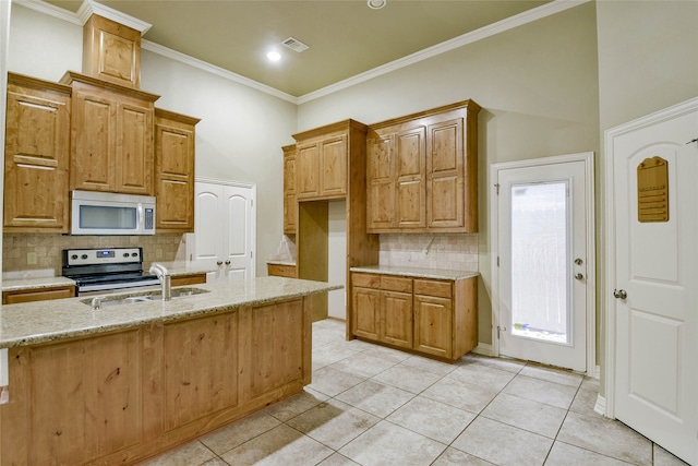 kitchen with a kitchen island with sink, light tile patterned floors, and light stone countertops