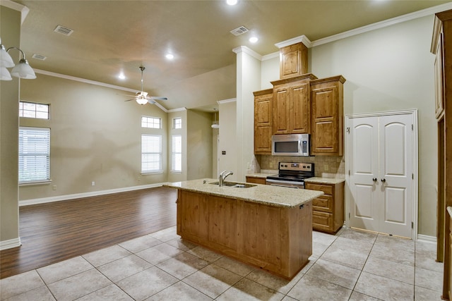 kitchen featuring sink, light hardwood / wood-style flooring, crown molding, an island with sink, and appliances with stainless steel finishes