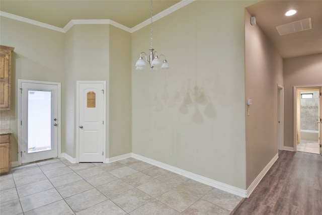 unfurnished dining area featuring crown molding, light tile patterned flooring, and an inviting chandelier