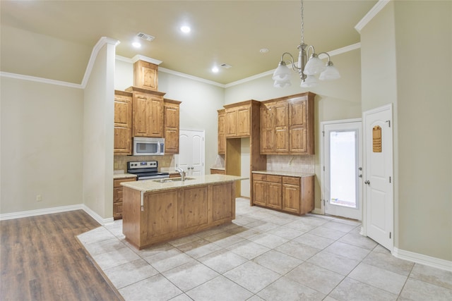 kitchen with appliances with stainless steel finishes, crown molding, and an island with sink