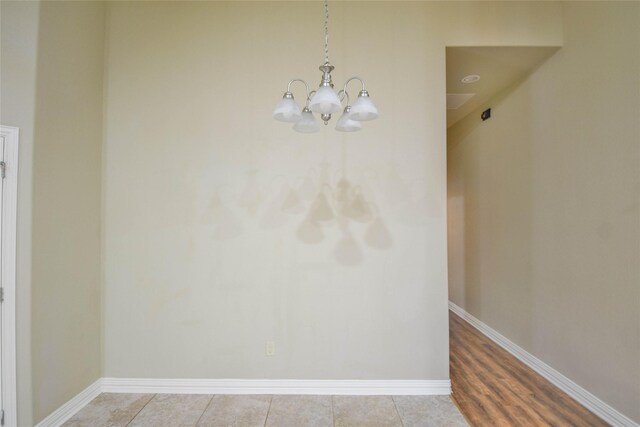 unfurnished room with hardwood / wood-style flooring and an inviting chandelier