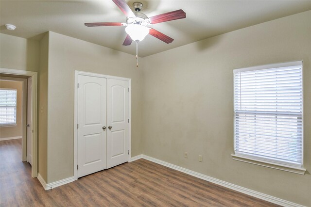 unfurnished bedroom with ceiling fan, a closet, dark hardwood / wood-style flooring, and multiple windows