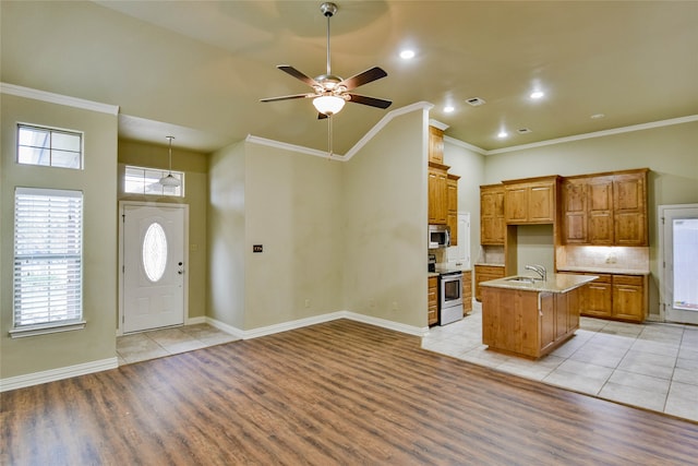 kitchen with appliances with stainless steel finishes, a kitchen island with sink, crown molding, ceiling fan, and light hardwood / wood-style flooring