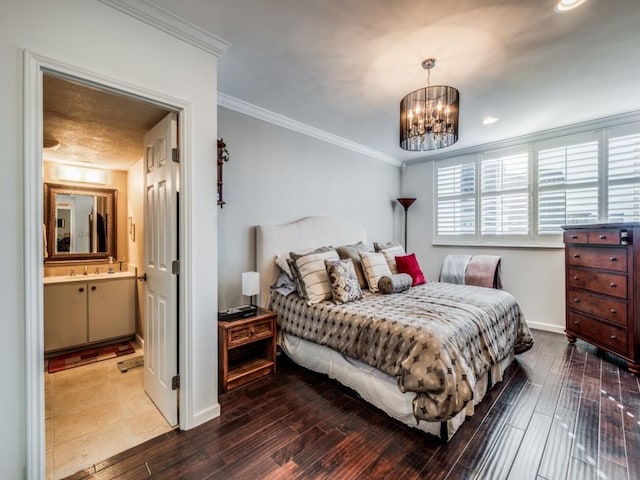 bedroom featuring an inviting chandelier, crown molding, ensuite bath, and hardwood / wood-style flooring