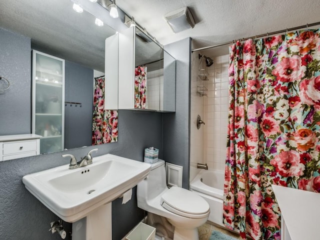 full bathroom featuring shower / tub combo with curtain, sink, toilet, and a textured ceiling