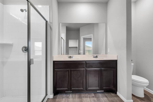 bathroom with hardwood / wood-style floors, vanity, toilet, and a shower with shower door