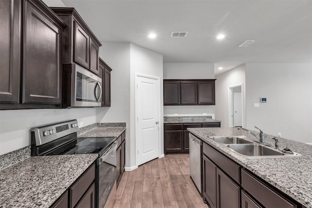 kitchen featuring sink, stainless steel appliances, dark brown cabinets, and light wood-type flooring