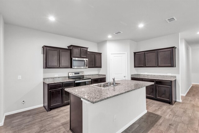 kitchen with sink, light wood-type flooring, a center island with sink, and appliances with stainless steel finishes