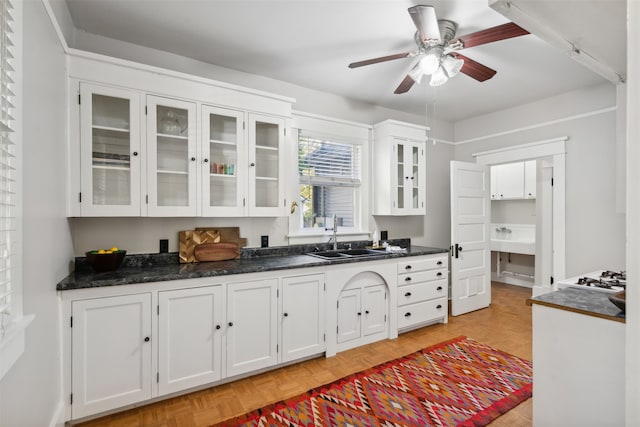 kitchen featuring ceiling fan, white cabinetry, sink, and light parquet flooring