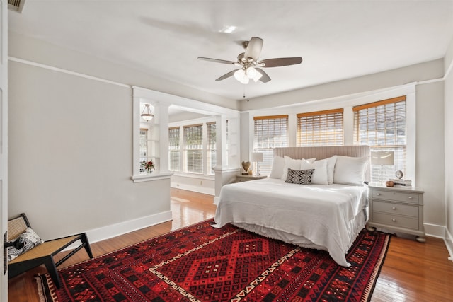 bedroom featuring hardwood / wood-style floors, ceiling fan, and multiple windows