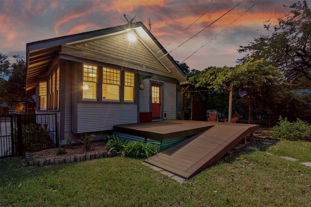 back house at dusk featuring a yard and a deck