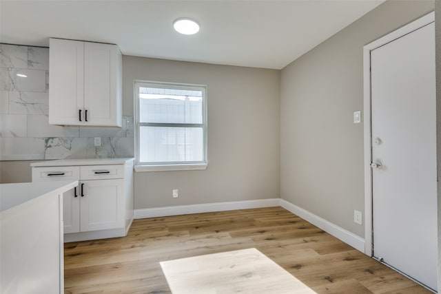 interior space with light hardwood / wood-style floors, white cabinetry, and backsplash