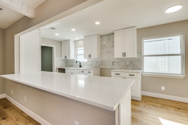 kitchen featuring light hardwood / wood-style floors, white cabinetry, sink, and tasteful backsplash