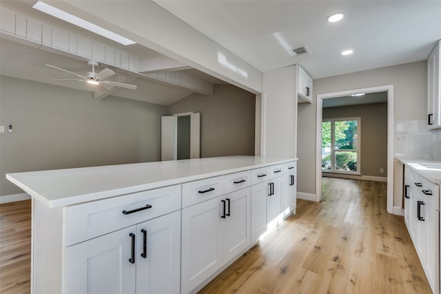 kitchen featuring ceiling fan, tasteful backsplash, vaulted ceiling with beams, light hardwood / wood-style floors, and white cabinets