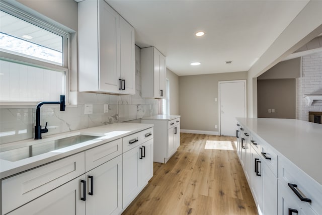 kitchen featuring white cabinets, backsplash, light hardwood / wood-style floors, and sink