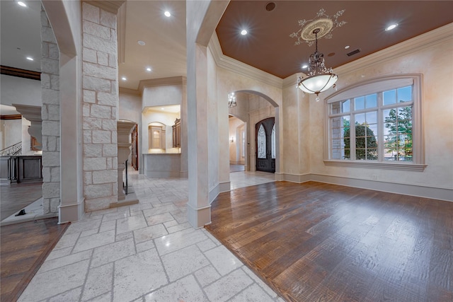 foyer entrance with decorative columns, a chandelier, and ornamental molding