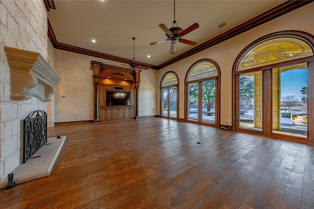 unfurnished living room featuring ceiling fan, crown molding, wood-type flooring, and a fireplace