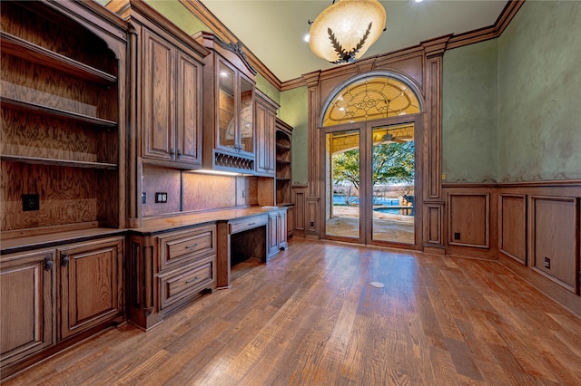 unfurnished office featuring built in desk, dark hardwood / wood-style floors, and ornamental molding