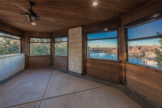 unfurnished sunroom featuring ceiling fan, a water view, and wooden ceiling