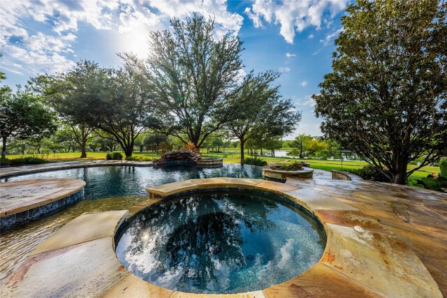 view of swimming pool featuring an in ground hot tub, a water view, and a lawn