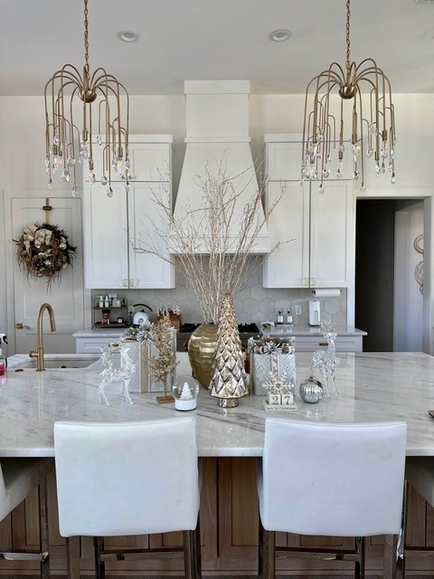 kitchen featuring white cabinetry, light stone countertops, sink, and backsplash