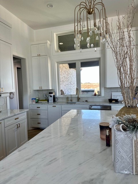 kitchen with white cabinetry, sink, light stone counters, and tasteful backsplash