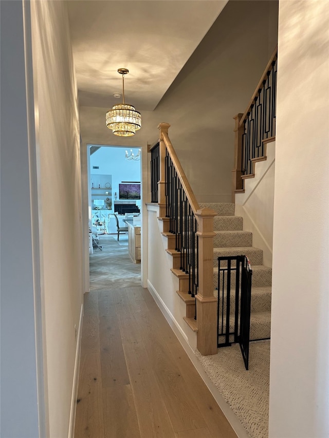 hallway with wood-type flooring and a notable chandelier