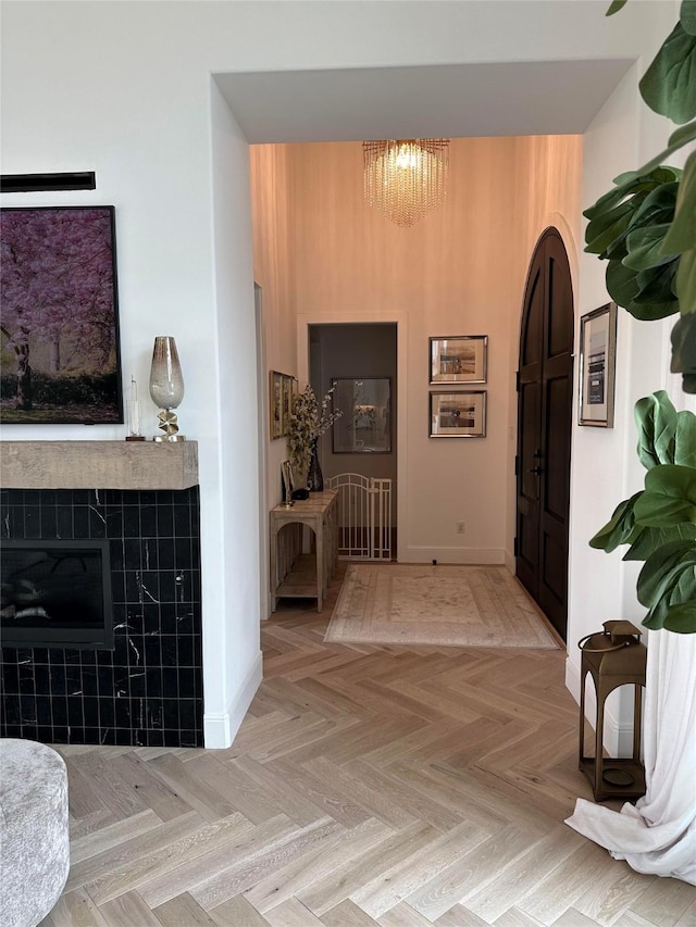 corridor with a notable chandelier, light parquet flooring, and a high ceiling