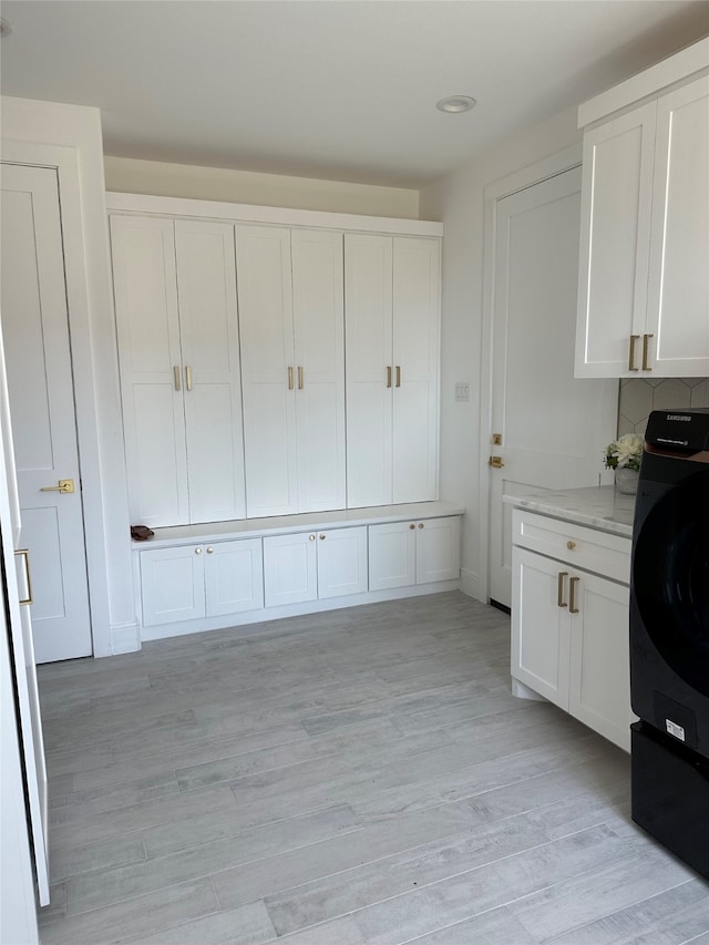 washroom featuring cabinets, washer / dryer, and light hardwood / wood-style flooring