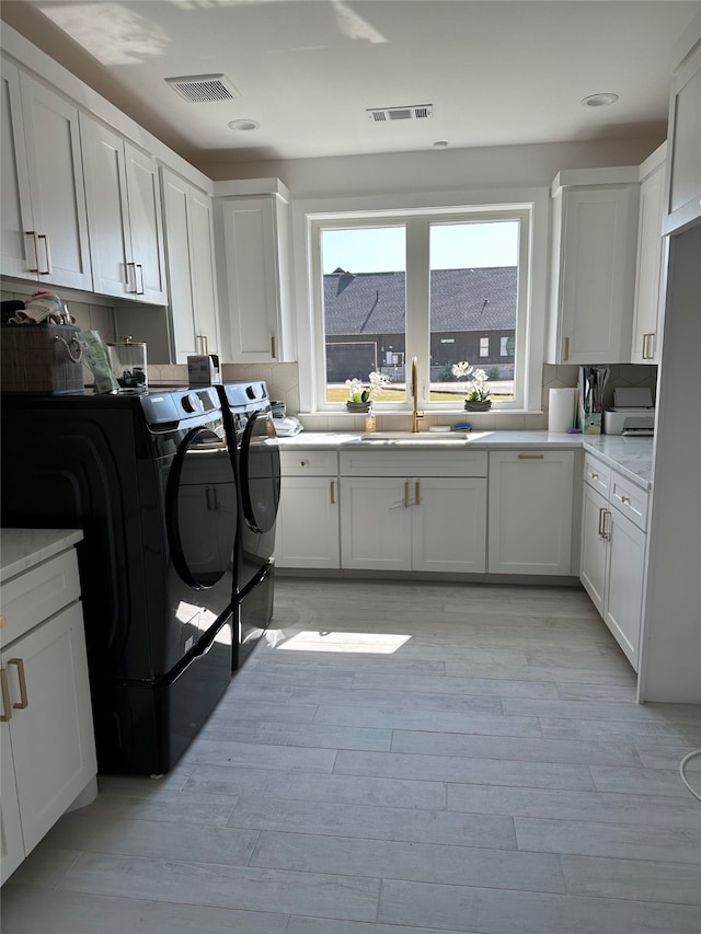 washroom featuring cabinets, sink, washer and clothes dryer, and light wood-type flooring