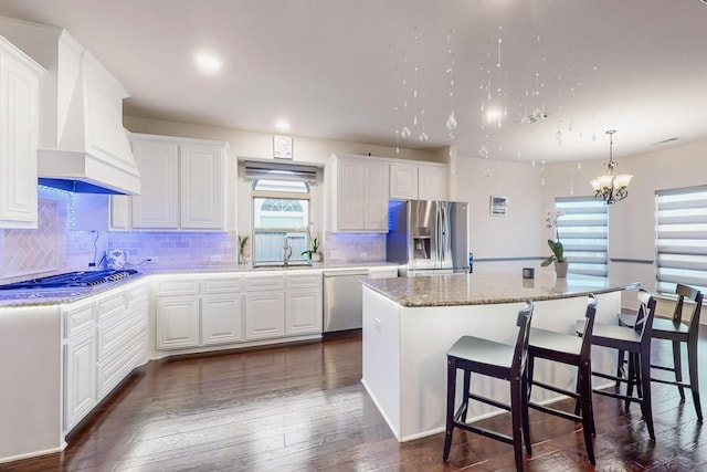 kitchen with white cabinetry, a kitchen island, custom exhaust hood, and appliances with stainless steel finishes