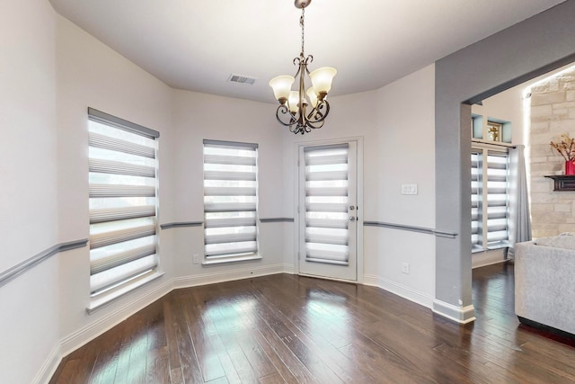 unfurnished dining area featuring dark hardwood / wood-style floors and an inviting chandelier