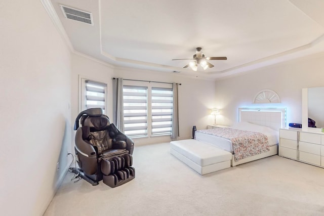 carpeted bedroom with a raised ceiling, crown molding, and ceiling fan