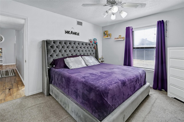 carpeted bedroom with ceiling fan and a textured ceiling