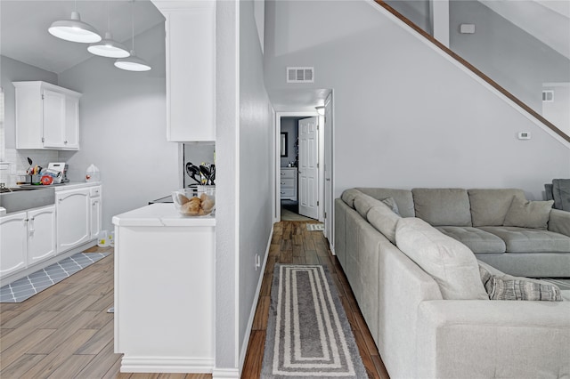 living room with high vaulted ceiling, sink, and light hardwood / wood-style floors